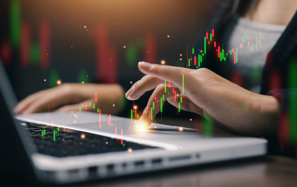 Stock,Market,Trading,Chart,Hologram,Above,Laptop,With,Businesswoman,Analyzing